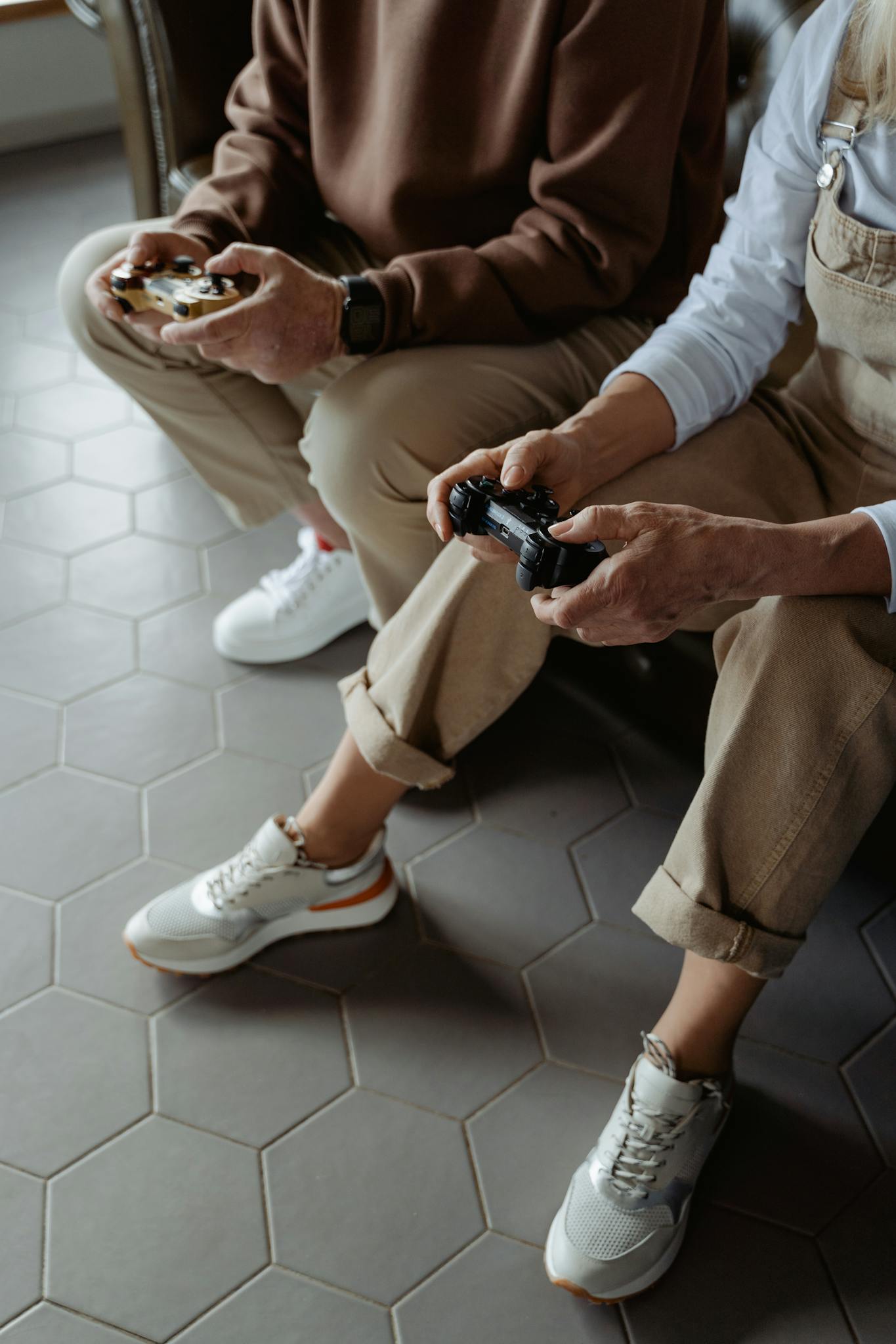 Close-up of two adults playing video games, showcasing their hands holding controllers while seated indoors.